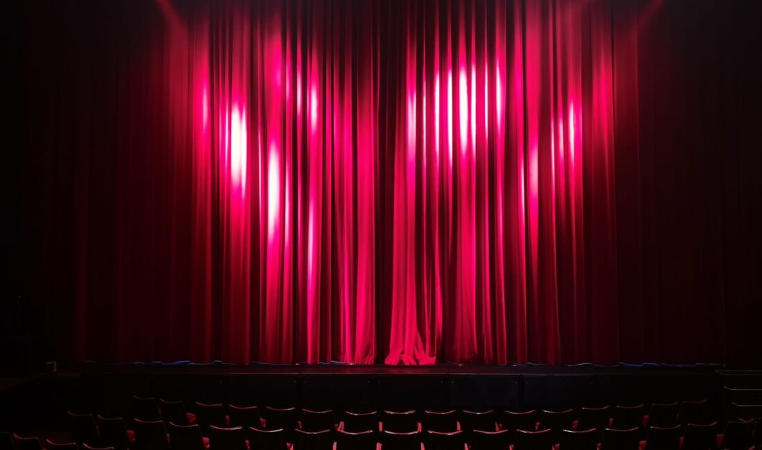 Scène de théâtre avec rideaux rouges et fauteuils vides