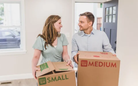 Couple transportant des cartons dans un nouveau logement